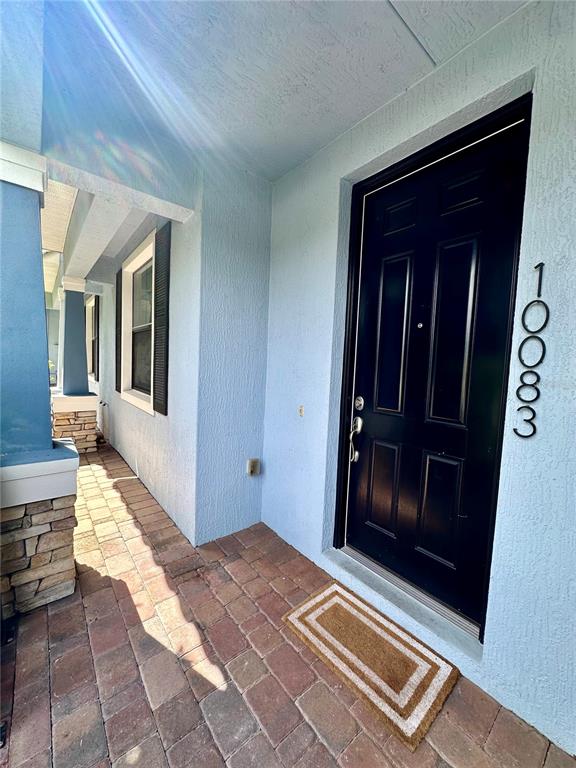 A front porch with brick pavers leads to a black front door on a blue house — 10083 EAGLE CREEK CENTER BOULEVARD, ORLANDO, FL