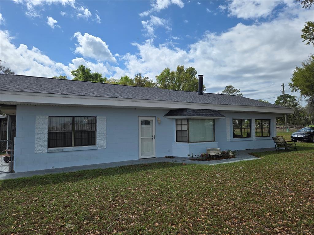 A light blue, single-story concrete block house with a dark shingled roof and lawn — 2327 CR 528, SUMTERVILLE, FL