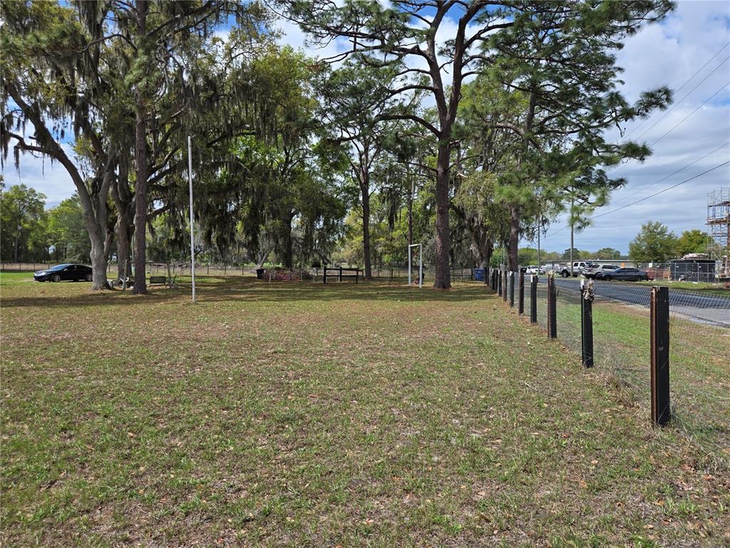 A grassy, fenced lot features several large trees and a soccer goal in the background — 2327 CR 528, SUMTERVILLE, FL