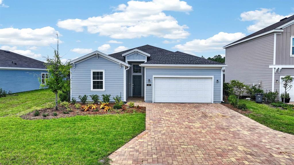 A single-story house with light blue siding, a two-car garage, and a paver driveway — 404 LAKE SINCLAIR STREET, ST AUGUSTINE, FL