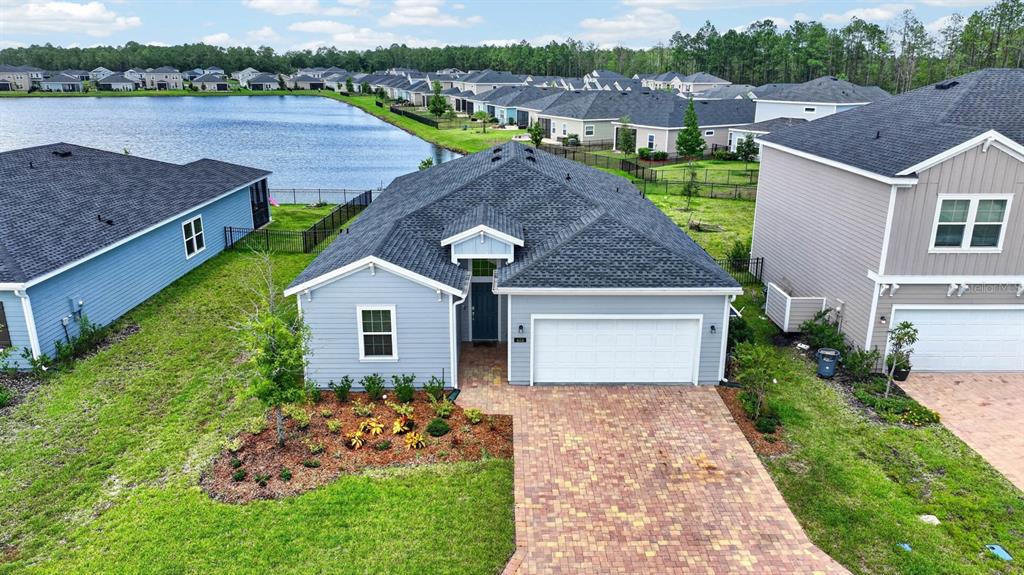 An aerial view shows a light blue single-story house with a paver driveway and garage — 404 LAKE SINCLAIR STREET, ST AUGUSTINE, FL