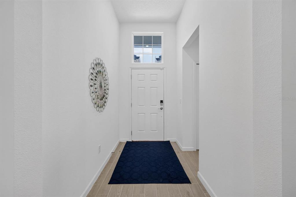 A bright entryway features white walls, a high ceiling, a front door, and tiled flooring — 404 LAKE SINCLAIR STREET, ST AUGUSTINE, FL