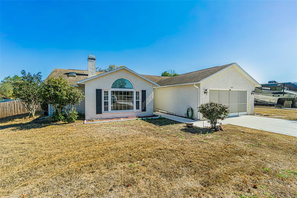 A single-story white brick house with a front-facing garage and a large arched window — 6056 SCHALEKAMP DRIVE, SPRING HILL, FL