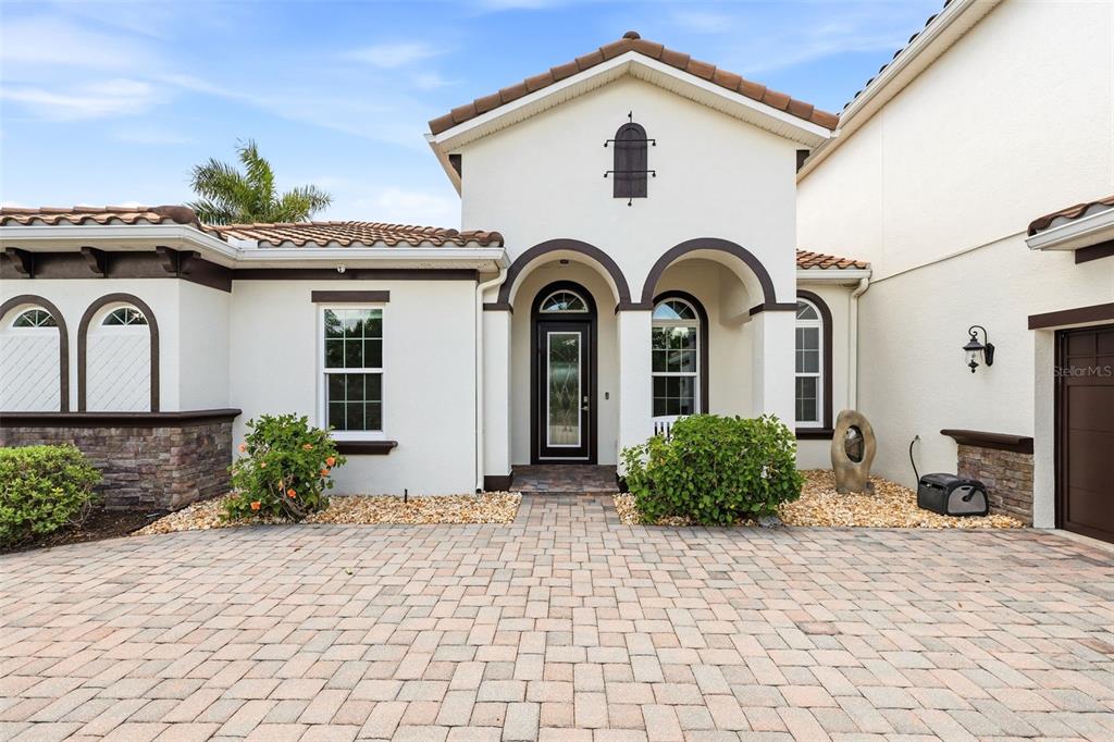 The exterior of a house features a paved driveway, arched entryway, and a tiled roof — 306 172ND STREET E, BRADENTON, FL