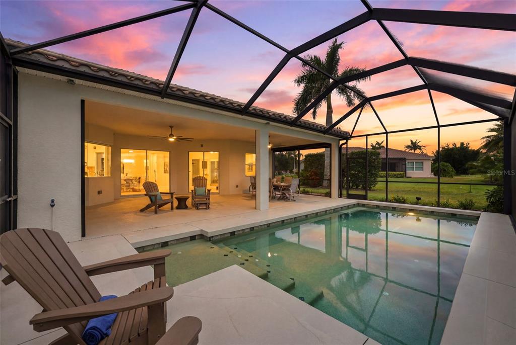 A covered swimming pool and patio area with outdoor furniture at sunset — 306 172ND STREET E, BRADENTON, FL