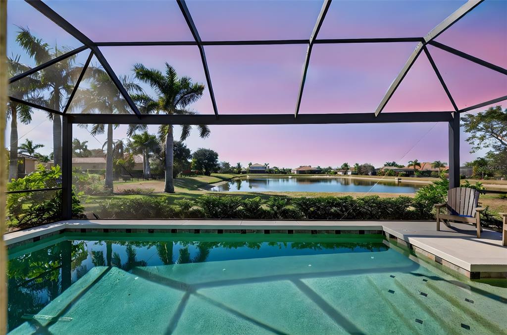 A screened-in pool patio overlooks a lake and residential neighborhood at sunset — 306 172ND STREET E, BRADENTON, FL