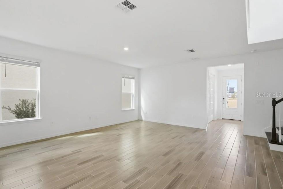 An empty living room with white walls, light wood-look tile flooring, and a front entryway — 14751 FIELD DAISY DRIVE, WINTER GARDEN, FL