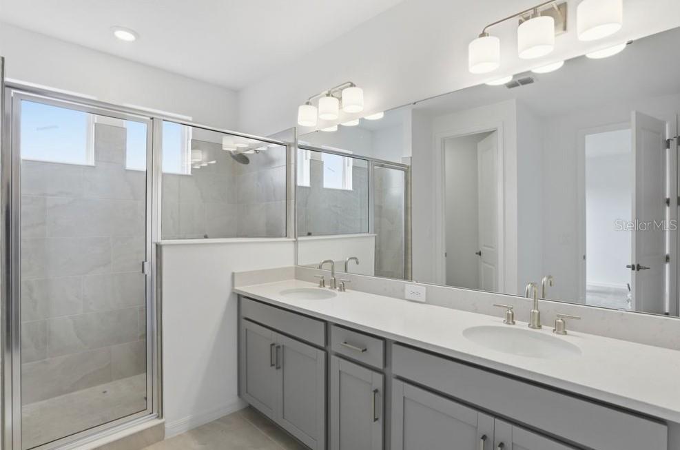 A bathroom features a double vanity with gray cabinets, a white countertop, and a glass shower — 14751 FIELD DAISY DRIVE, WINTER GARDEN, FL
