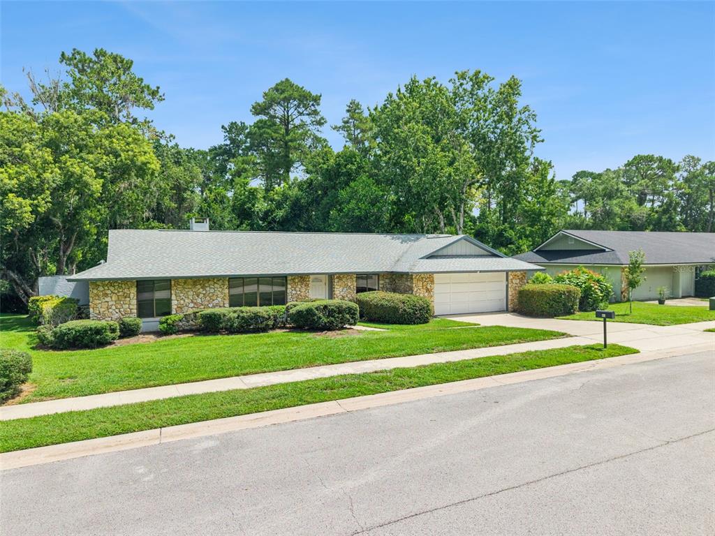 A single-story house with a stone facade, a two-car garage, and a green lawn — 211 HICKORY DRIVE, LONGWOOD, FL