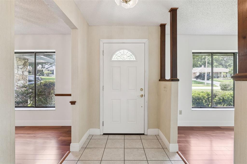 An entryway with tiled flooring, a white front door, and wood-look flooring in adjacent rooms — 211 HICKORY DRIVE, LONGWOOD, FL