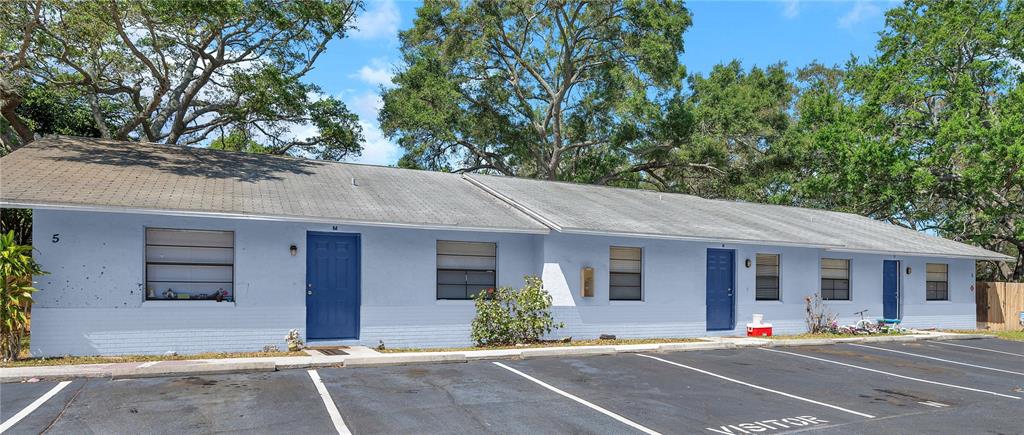 A single-story light blue apartment building with a parking lot in the foreground — 950 BELTREES STREET, DUNEDIN, FL