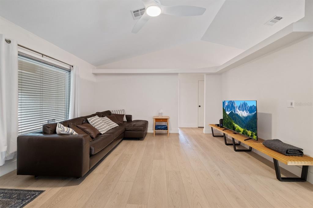 A living room features a brown sectional sofa, a television on a bench, and light wood flooring — 12630 MAGNOLIA STREET, SAN ANTONIO, FL