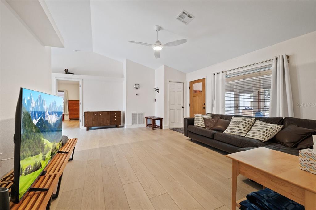A living room features light wood flooring, a ceiling fan, a television, and a sectional sofa — 12630 MAGNOLIA STREET, SAN ANTONIO, FL