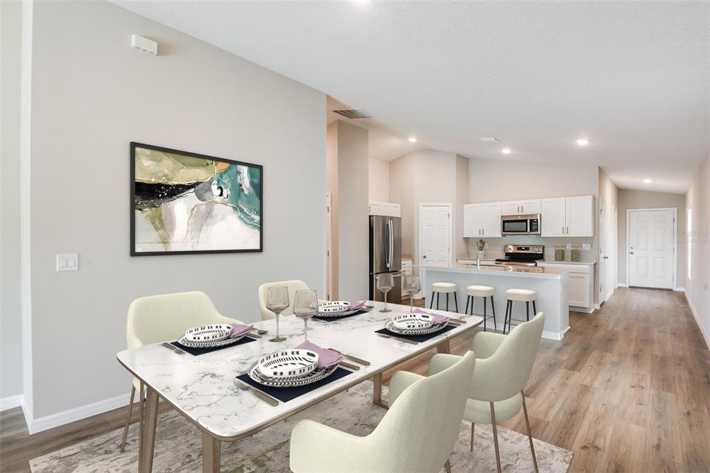 A dining area with a marble-top table leads into a kitchen with white cabinetry — 15250 MAUDE LANDING LOOP, WIMAUMA, FL
