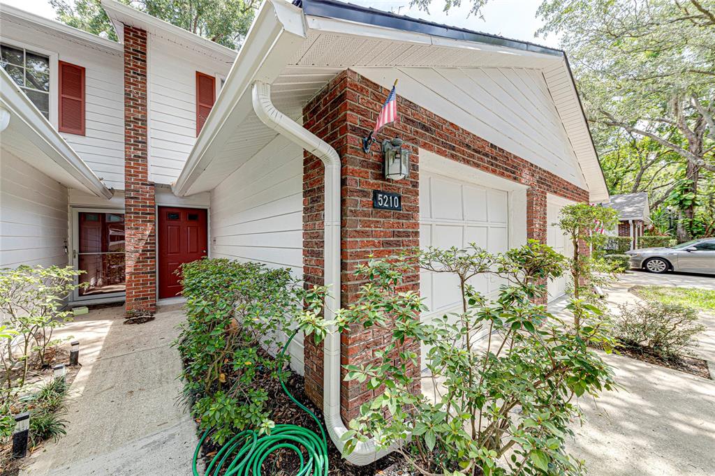 A brick and white siding house exterior features a red front door and garage — 5210 LAZY OAKS DRIVE, WINTER PARK, FL