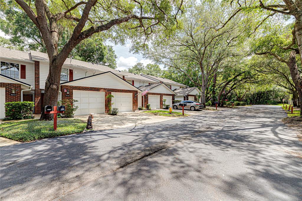 A row of attached townhomes with brick and white siding features garages and mature trees — 5210 LAZY OAKS DRIVE, WINTER PARK, FL