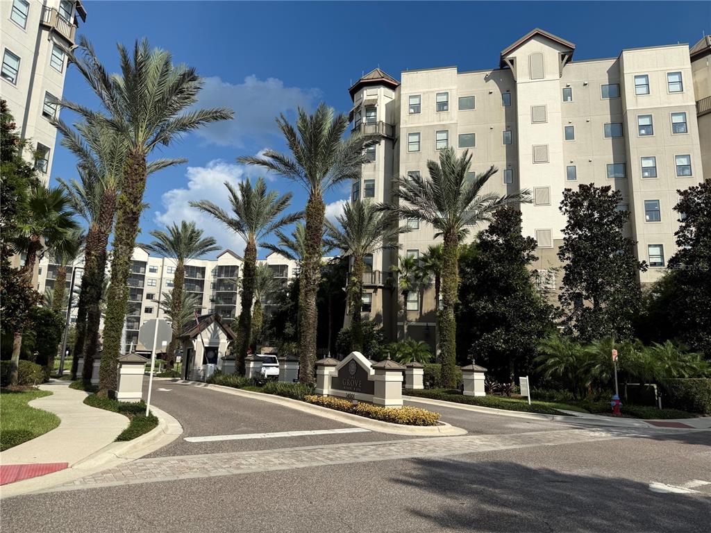 A multi-story resort building stands behind a gated entrance with palm trees and landscaping — 14501 GROVE RESORT AVENUE UNIT 2703, WINTER GARDEN, FL