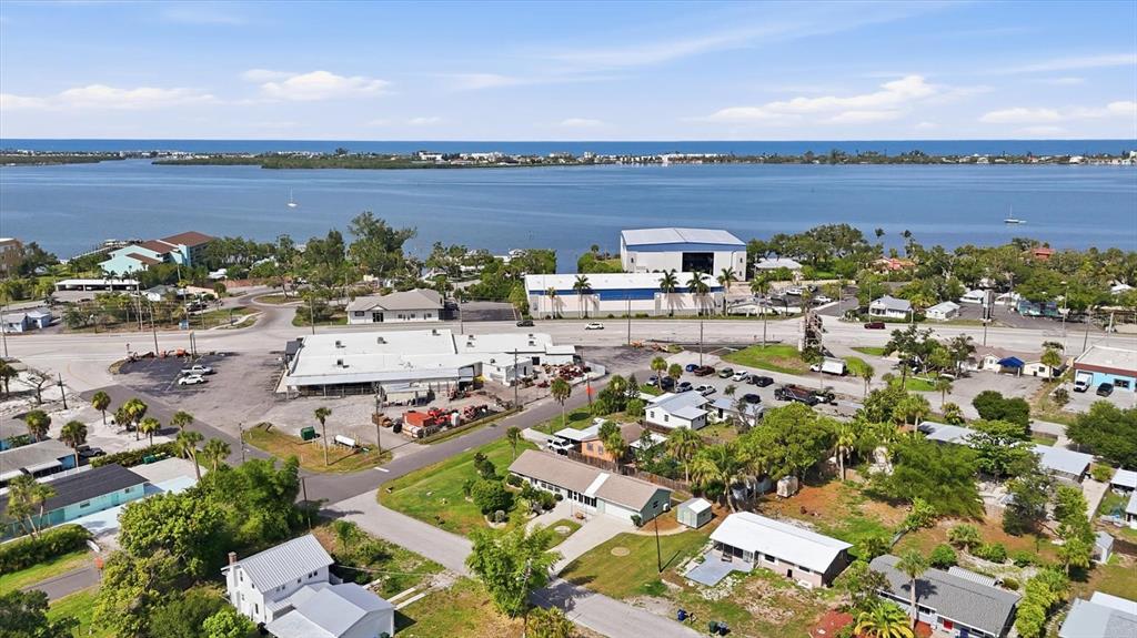 An aerial view shows a coastal neighborhood with houses, commercial buildings, and a large bay — 898 S BROADWAY, ENGLEWOOD, FL