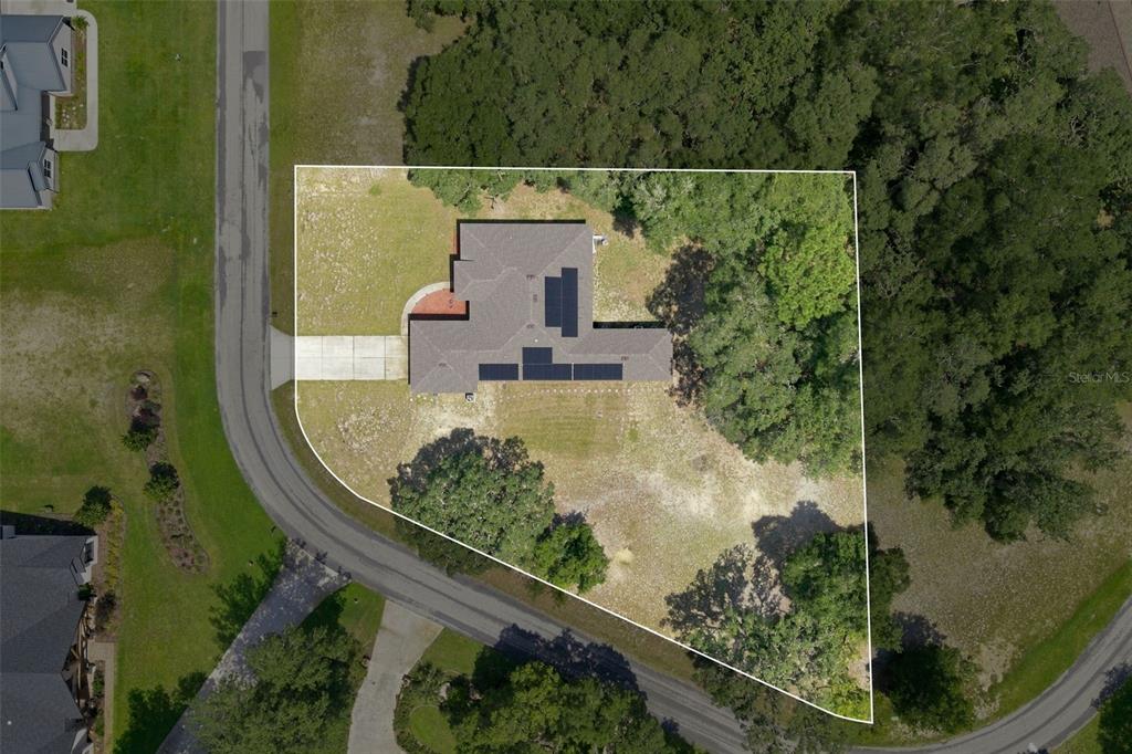 An aerial view shows a house with solar panels on a large, partially wooded lot — 9495 E BAYMEADOWS DRIVE, INVERNESS, FL