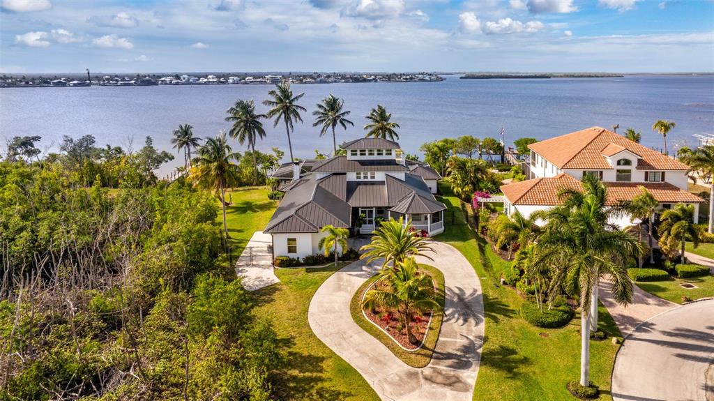 An aerial view shows two waterfront houses with palm trees and a shared driveway — 12201 SHOREVIEW DRIVE, MATLACHA, FL