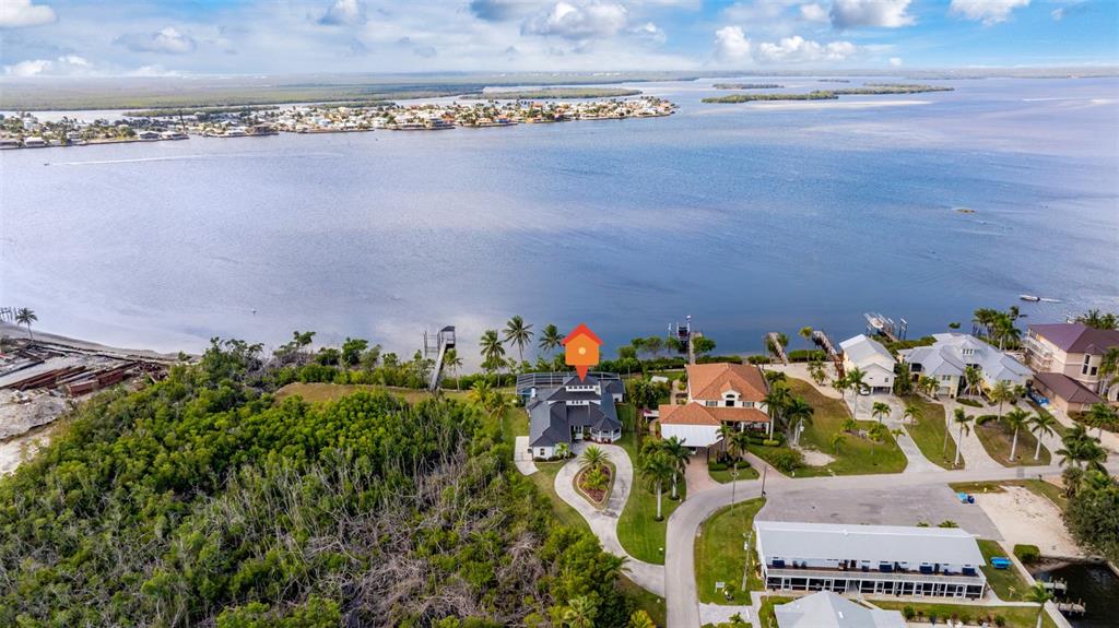 An aerial view shows a waterfront house with a pool and dock near a bay — 12201 SHOREVIEW DRIVE, MATLACHA, FL