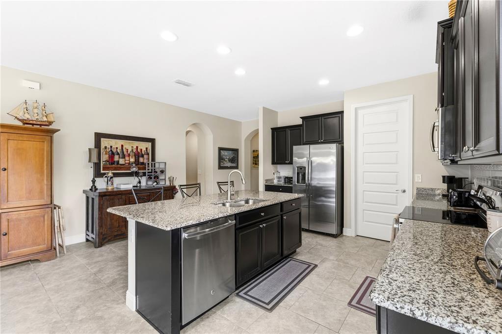 A kitchen with dark cabinets, granite countertops, a center island, and stainless steel appliances — 8711 EDEN COVE DRIVE, WINTER GARDEN, FL