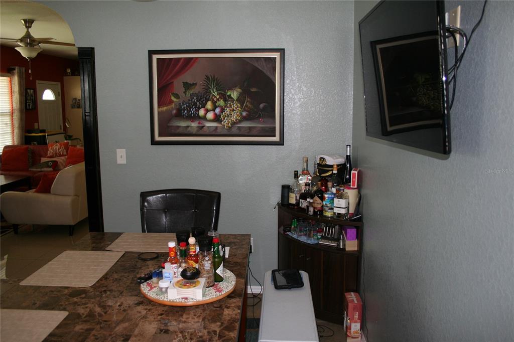 A dining area features a dark table, a corner bar cabinet, and a framed fruit painting — 236 NE 13TH PLACE, OCALA, FL