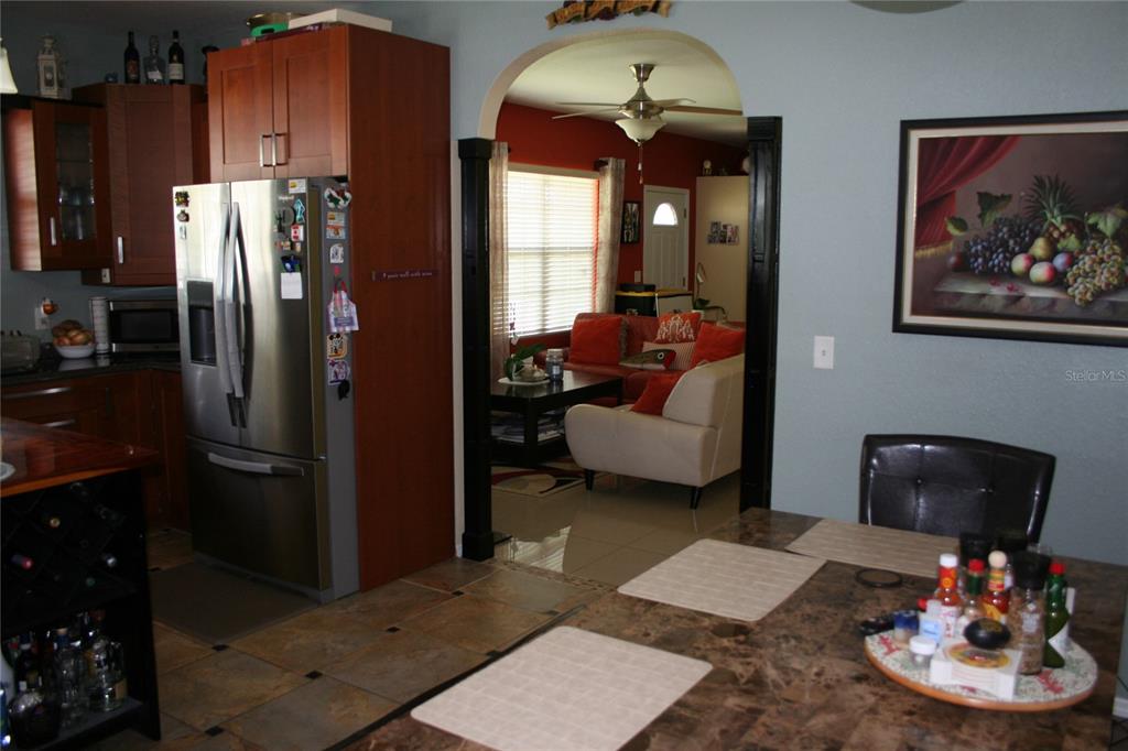 A kitchen with dark wood cabinets and stainless steel appliances opens into a living room — 236 NE 13TH PLACE, OCALA, FL