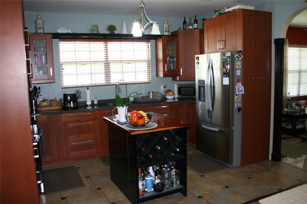 A kitchen features wood cabinets, stainless steel appliances, a center island, and tile flooring — 236 NE 13TH PLACE, OCALA, FL
