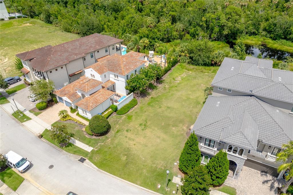 An aerial view shows a vacant residential lot situated between two large multi-story houses — 594 MUIRFIELD LOOP, REUNION, FL