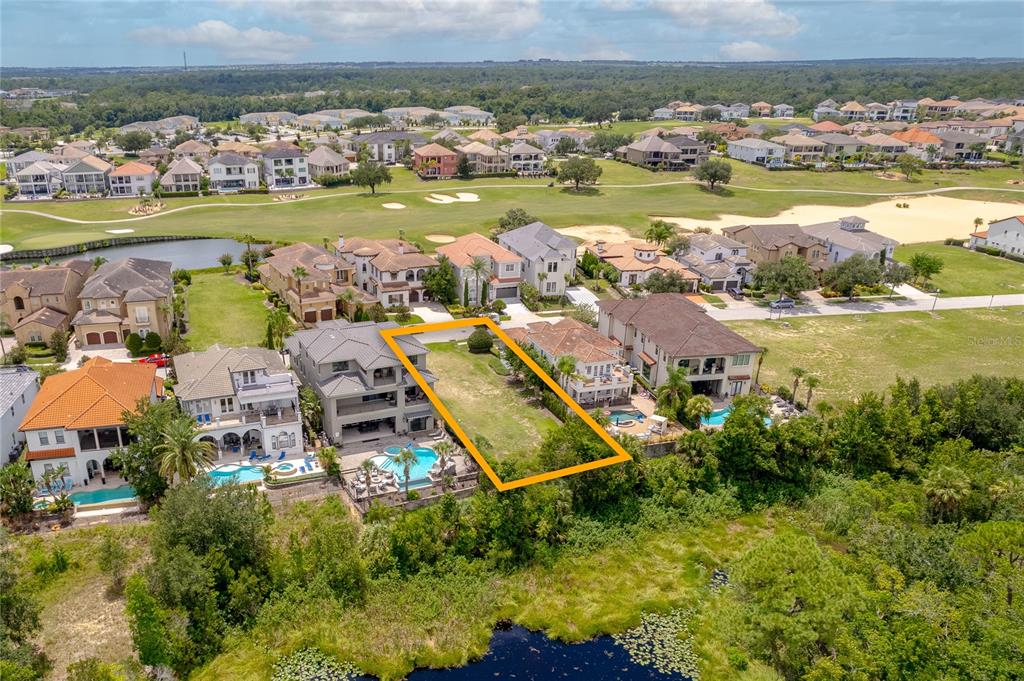 An aerial view shows a vacant residential lot situated between two large houses — 594 MUIRFIELD LOOP, REUNION, FL