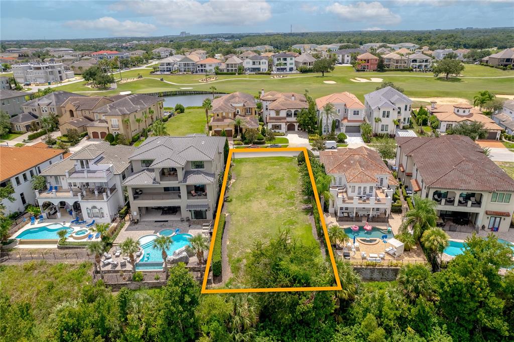 An aerial view shows a vacant rectangular lot situated between two large residential homes — 594 MUIRFIELD LOOP, REUNION, FL