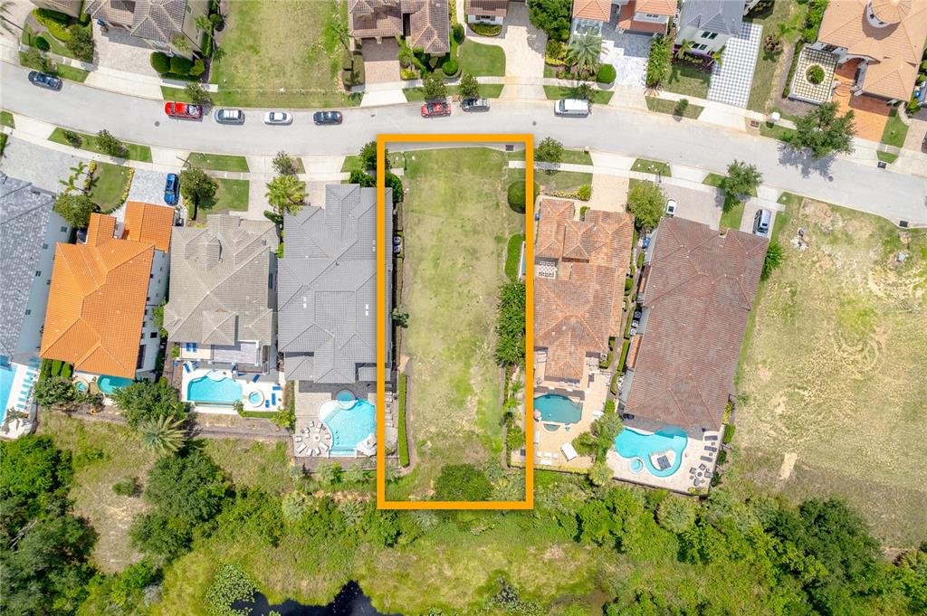 An aerial view shows a vacant residential lot outlined in orange between two houses — 594 MUIRFIELD LOOP, REUNION, FL