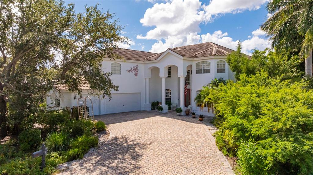 An aerial view shows a single-family home with a paved driveway surrounded by lush trees — 13881 BLENHEIM TRAIL ROAD, FORT MYERS, FL