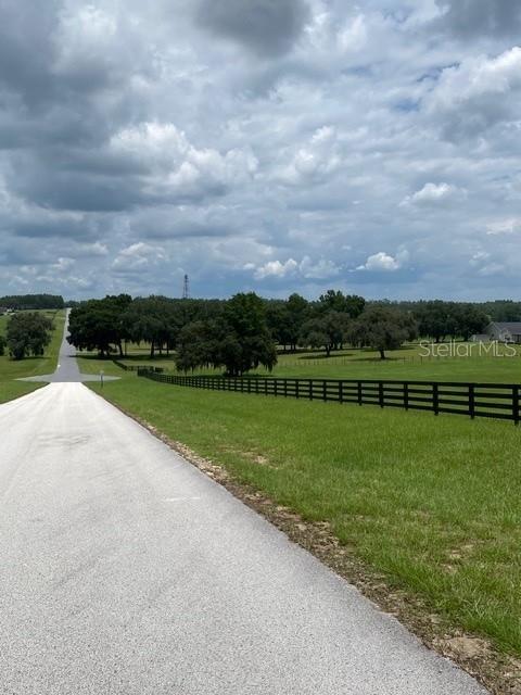 A paved driveway stretches through a grassy field toward a distant tree line — 5610 EAST ORION CT, FLORAL CITY, FL