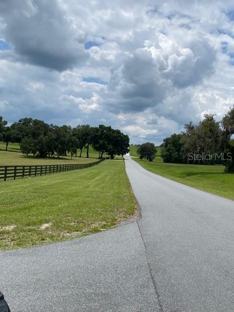 A paved driveway leads to a grassy lot enclosed by a black wooden fence — 5610 EAST ORION CT, FLORAL CITY, FL