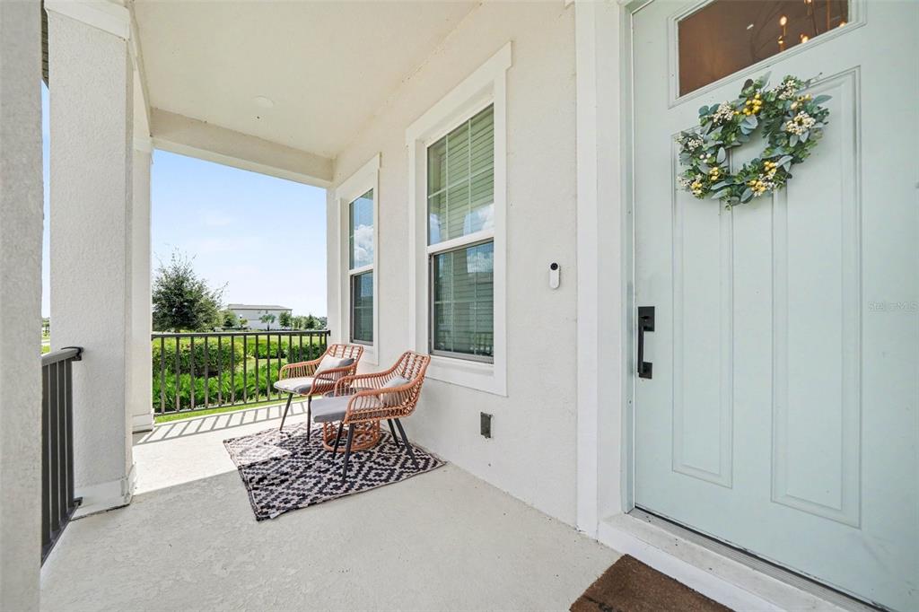 A covered front porch features two wicker chairs, a patterned rug, and a light blue door — 16260 SILVER GROVE BLVD, WINTER GARDEN, FL