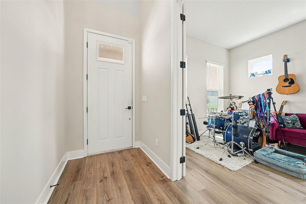 A white front door opens into a foyer with wood-look flooring and an adjacent music room — 16260 SILVER GROVE BLVD, WINTER GARDEN, FL