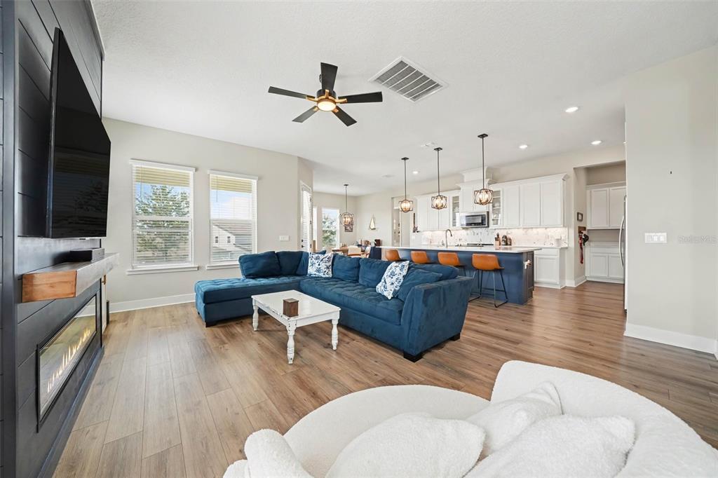 An open-concept living room features a blue sectional sofa, a fireplace, and a kitchen island — 16260 SILVER GROVE BLVD, WINTER GARDEN, FL