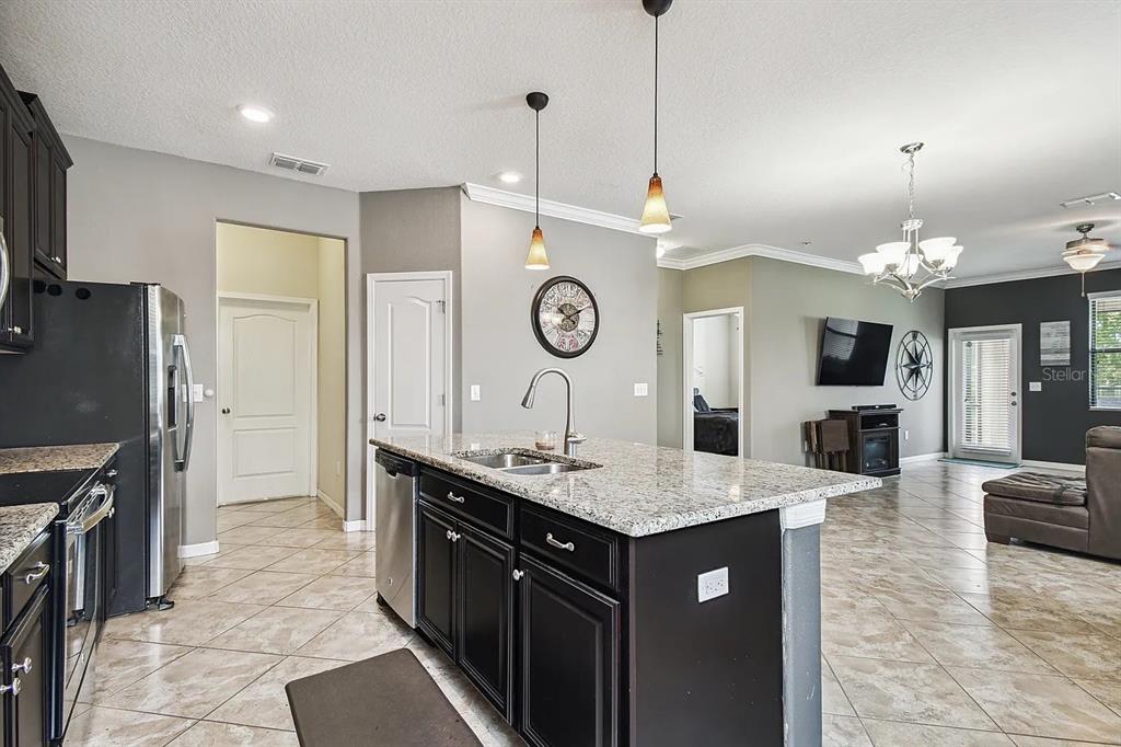 A kitchen with a granite-topped island and dark cabinets opens into a living area — 11714 LAKE BOULEVARD, NEW PORT RICHEY, FL
