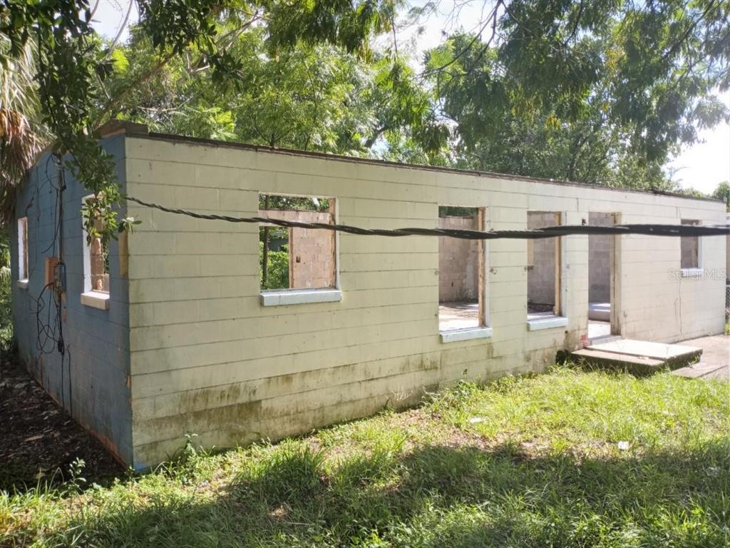 An exterior view of a dilapidated, single-story concrete block structure with missing windows and doors — 4022 SHELLMAN STREET, ORLANDO, FL