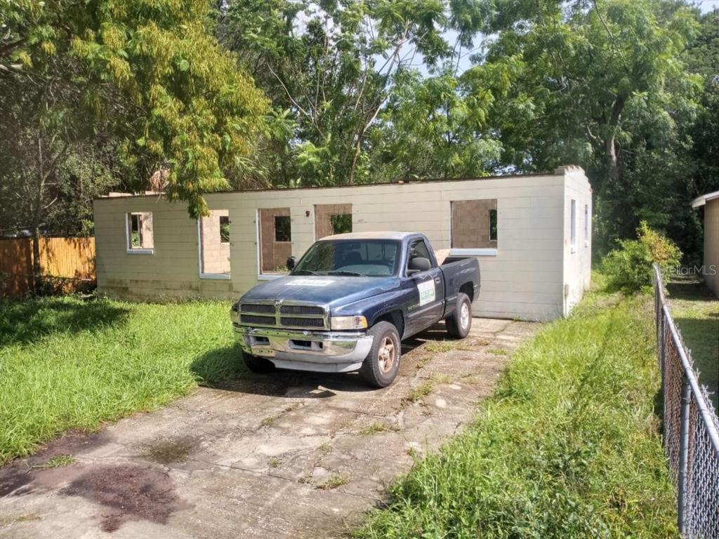 A blue pickup truck is parked in front of a dilapidated, roofless concrete block structure — 4022 SHELLMAN STREET, ORLANDO, FL