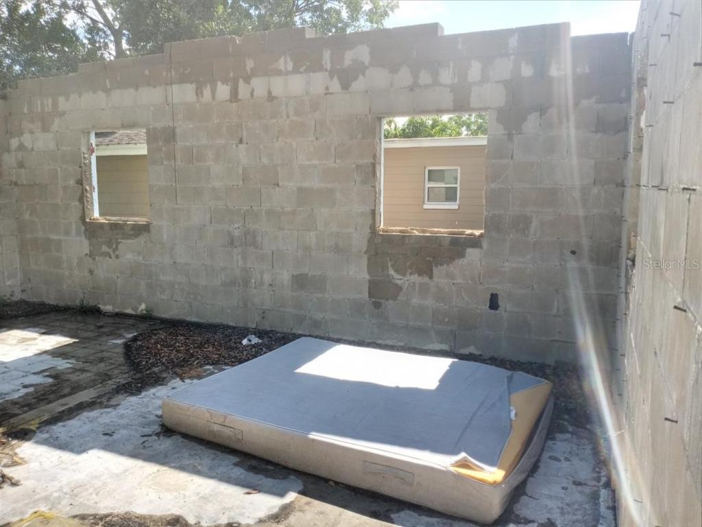 An unfinished concrete block wall with two window openings and a mattress on the floor — 4022 SHELLMAN STREET, ORLANDO, FL