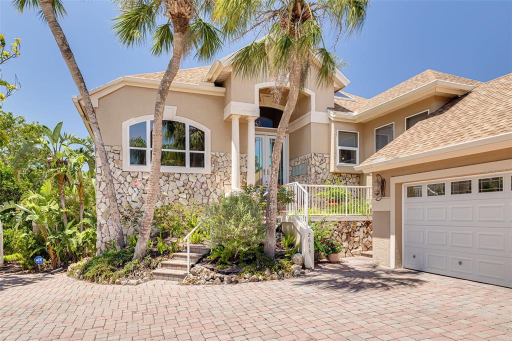 A two-story house with a stone facade, palm trees, and a paved driveway — 2613 59TH STREET S, GULFPORT, FL