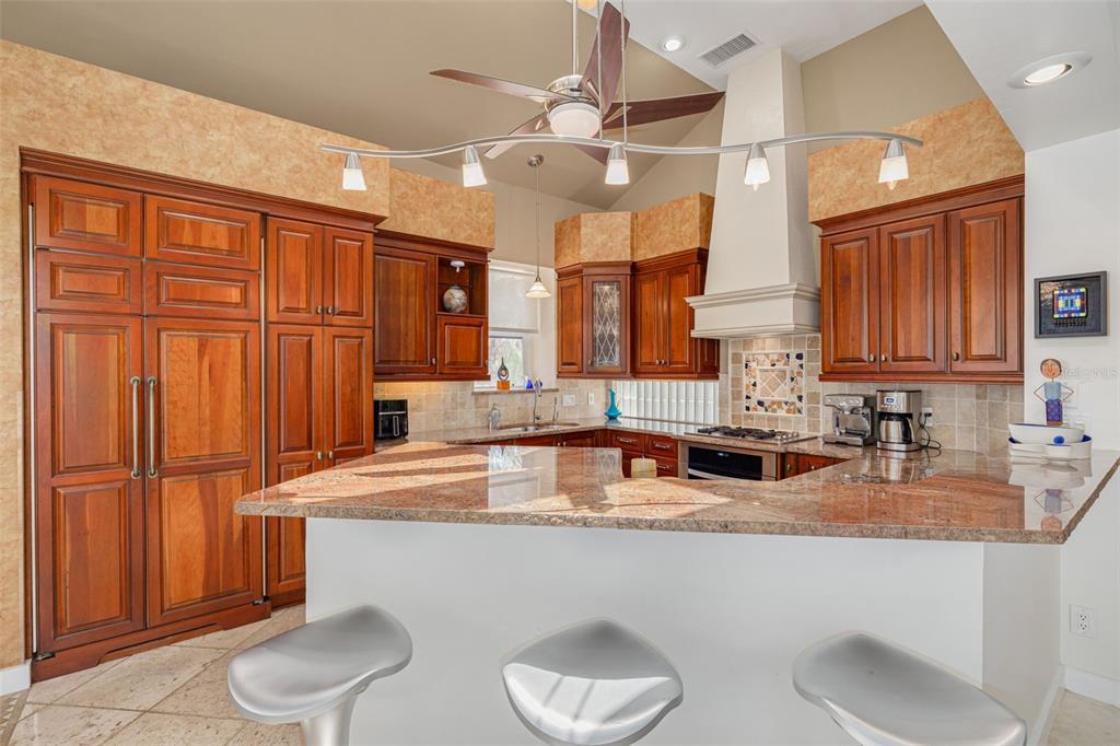 A kitchen features wood cabinetry, granite countertops, a breakfast bar with stools, and stainless appliances — 2613 59TH STREET S, GULFPORT, FL