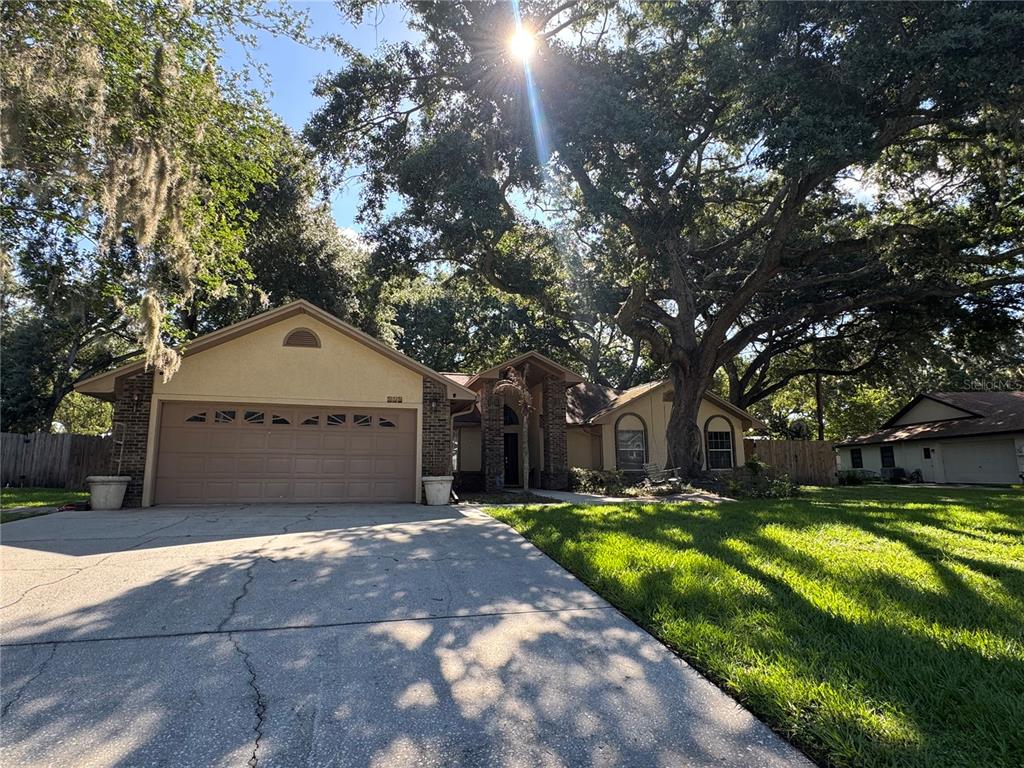 A single-story house with a two-car garage and a large oak tree in the yard — 915 HEATHERBROOK DRIVE, AUBURNDALE, FL