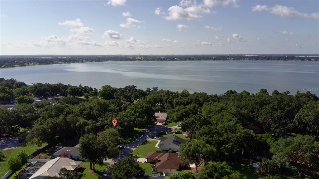 An aerial view shows a residential neighborhood with a large lake in the background — 915 HEATHERBROOK DRIVE, AUBURNDALE, FL