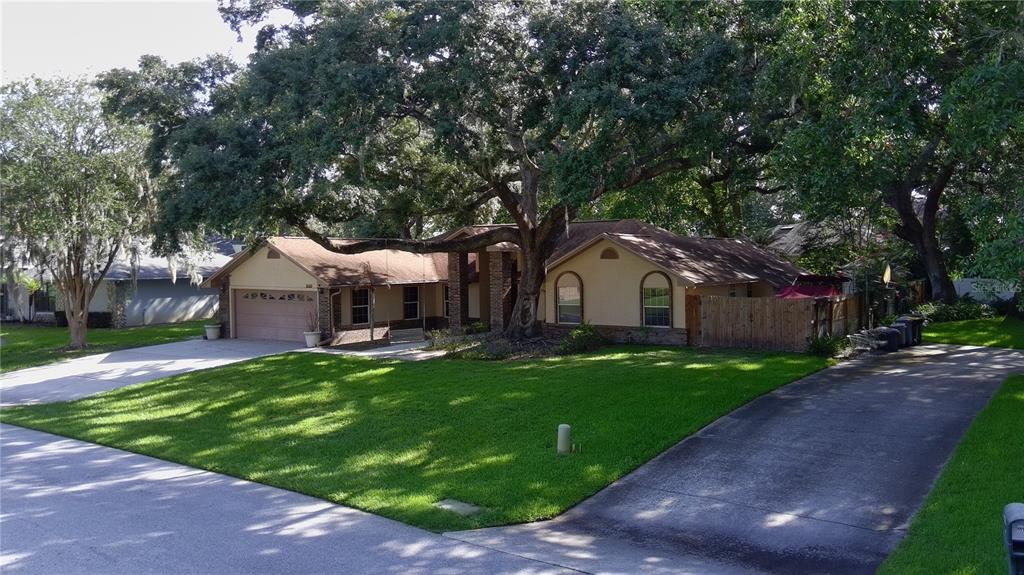 A single-story house with a two-car garage, a large oak tree, and a concrete driveway — 915 HEATHERBROOK DRIVE, AUBURNDALE, FL