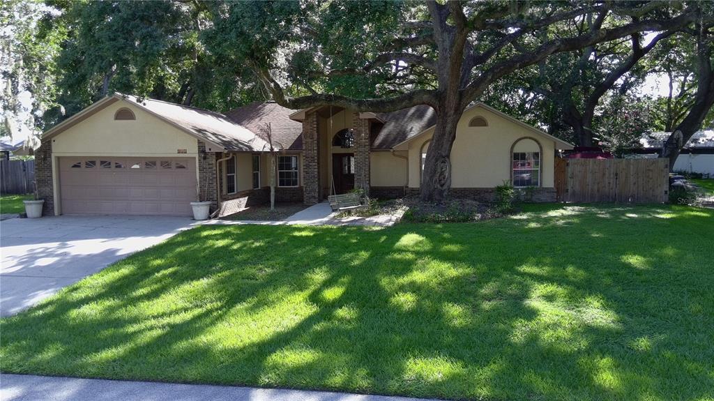 A single-story house with a two-car garage, brick accents, and a large tree in front — 915 HEATHERBROOK DRIVE, AUBURNDALE, FL