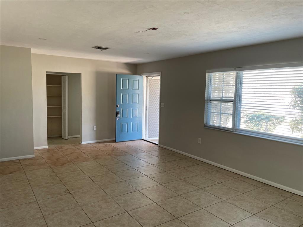 An interior view of a living room with tile flooring, a blue door, and windows — 10307 SANDPIPER ROAD W, BRADENTON, FL